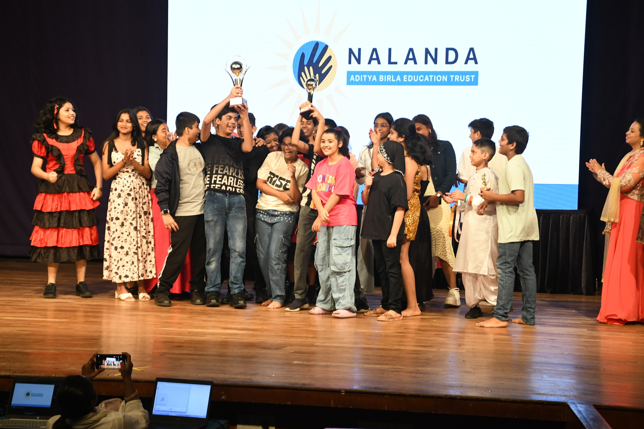 Students celebrating with their trophy on stage